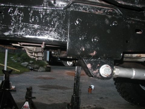 1994 Ford Bronco - The underside of a vehicle is shown, supported by jack stands, with a focus on the frame and suspension components.