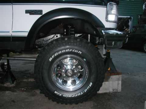 1994 Ford Bronco - A white Ford Bronco is shown lifted on jack stands, revealing its suspension and BFGoodrich tires.