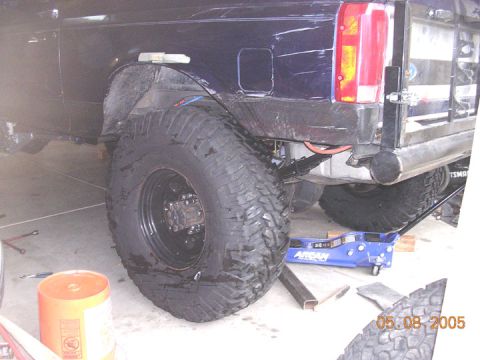 1994 Ford Bronco - The rear suspension and axle of a Jeep Cherokee XJ are visible, with a floor jack supporting the vehicle.
