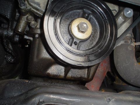 1993 Ford Taurus - Close-up view of an engine's harmonic balancer, showing signs of oil leakage and a portion of the exhaust system.