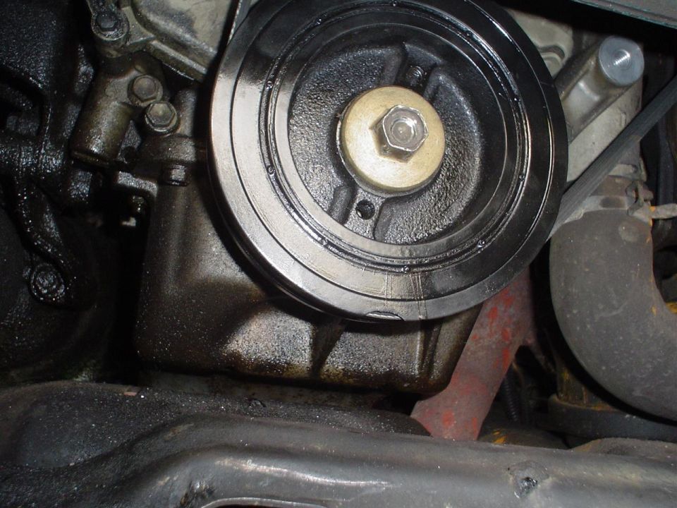 Engine harmonic balancer with oil leaks and a rusty exhaust manifold