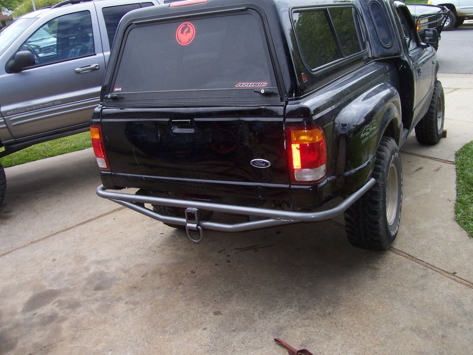 Rear corner of black Ford pickup showing tube bumper and silver wheel on mud tire