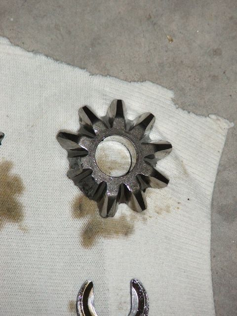 1989 Ford Bronco - A close-up of a damaged differential spider gear, showing chipped teeth, resting on a white cloth.