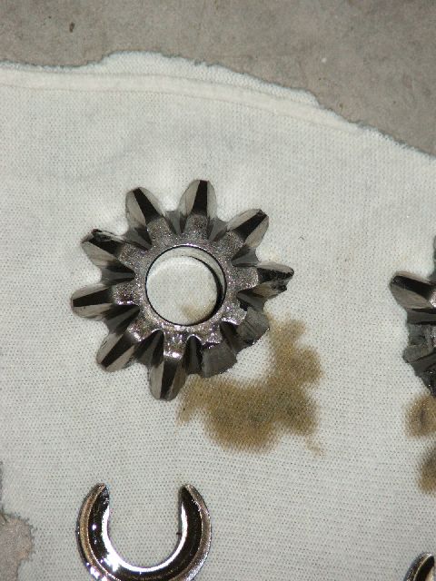 1989 Ford Bronco - Close-up of differential spider gears, possibly damaged, with oil stains and a tool.