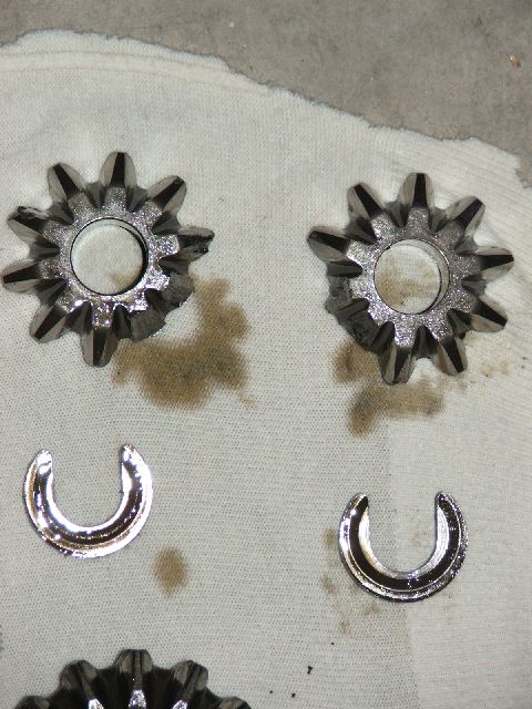 1989 Ford Bronco - Differential gears and c-clips are shown on a white cloth with oil stains.