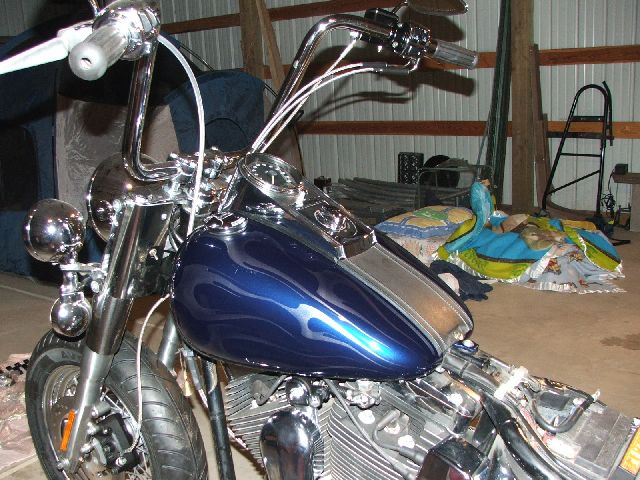 Blue ghost-flame tank and chrome speedometer viewed from the rider's seat