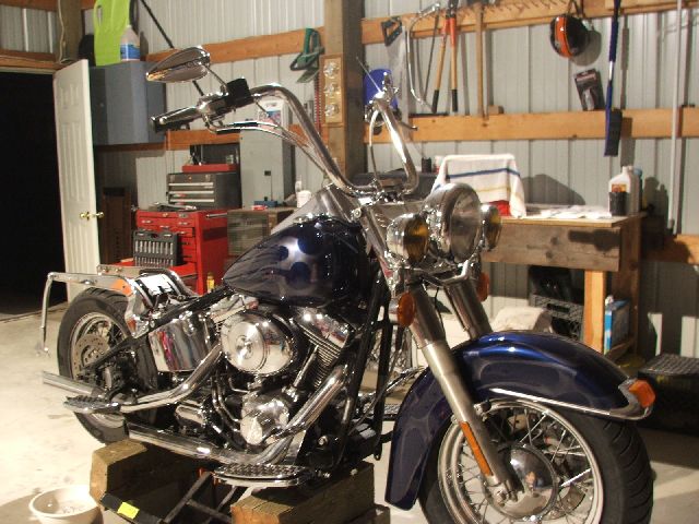 Blue custom cruiser with chrome V-twin raised on a lift in a workshop