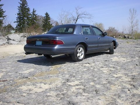 1985 Mercury Grand Marquis - The rear view of a blue Mercury Grand Marquis shows its taillights and exhaust pipes.