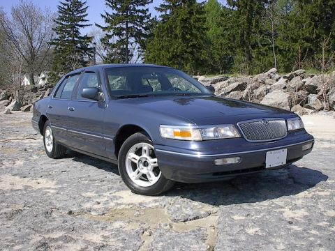 1985 Mercury Grand Marquis - This Mercury Grand Marquis features a distinctive grille and is parked outdoors on a rocky surface.