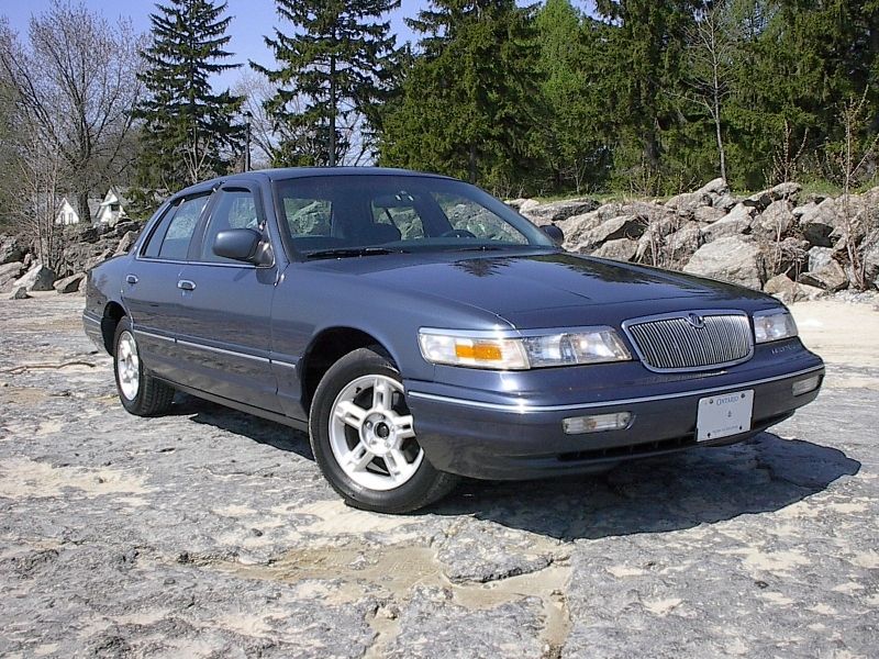 Blue-gray Mercury Grand Marquis sedan front three-quarter on rock shelf