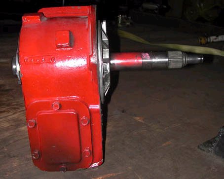 1971 Ford Bronco - A red metal gearbox with a splined shaft is shown on a wooden surface.