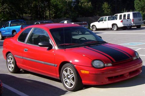 1997 Ford Taurus - Red coupe with black racing stripes parked in a lot with other vehicles visible.