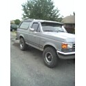1995 Ford Bronco - Very small, low-resolution thumbnail of a silver-gray late-1980s Ford Bronco full-size SUV parked on a driveway, viewed from the front thre…