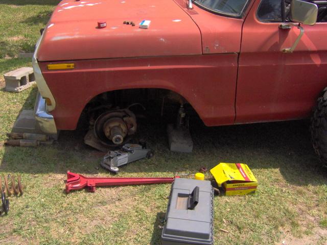1979 Ford Bronco with front wheel off, jacked up, and tools on the ground