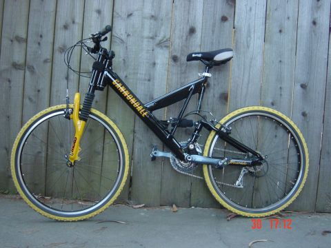 1990 Ford Bronco - Cannondale mountain bike with yellow fork and tires against a wooden fence.