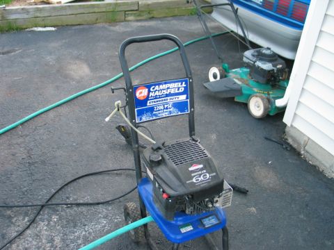1995 Ford Bronco - A pressure washer and lawn mower sit on a driveway next to a blue vehicle and a house.