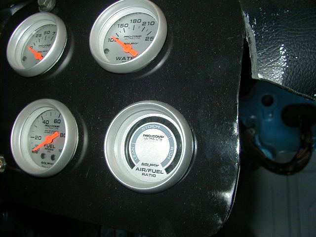 Dashboard with four Pro-Comp gauges: water temperature, fuel pressure, and air/fuel ratio. The panel is black and shows some wear