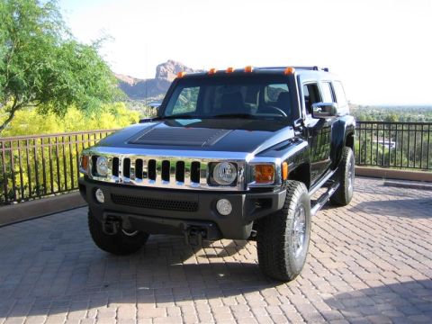 1994 Ford Bronco - A black Hummer H3 SUV is parked on a brick driveway with a mountainous landscape in the background.