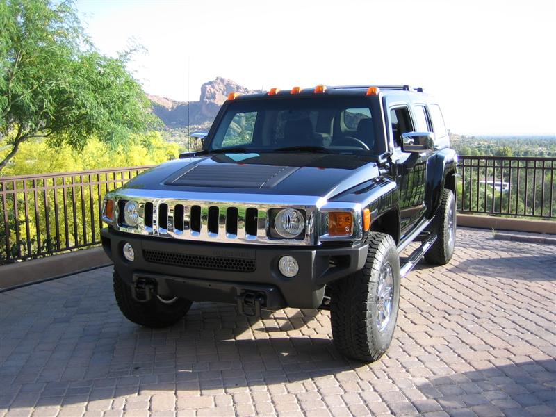 Black Hummer H3 SUV parked on brick driveway, front quarter view