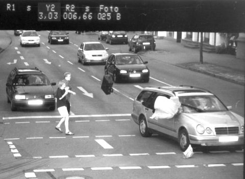 1990 Ford Bronco - A traffic camera captured pedestrians crossing a street as vehicles wait, with a large white object protruding from a car window.