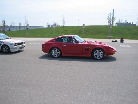 1993 Ford Probe - A red sports car with racing number 121 is parked next to another vehicle on a paved lot.