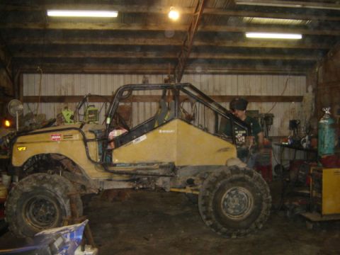 1989 Ford Bronco - A heavily modified off-road vehicle with a custom roll cage sits in a workshop.