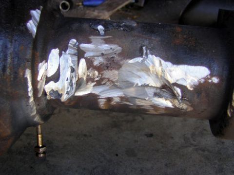 1995 Ford Bronco - Close-up of a rusty axle housing tube with fresh silver weld beads and grinder marks built up along its underside, likely a repair or brack…