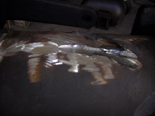Close-up of a metal part with visible weld marks and some threaded components