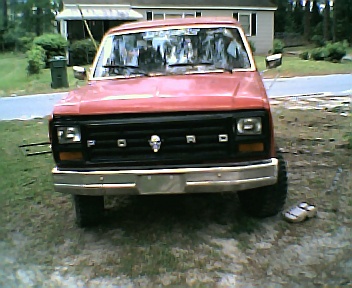 1985 Ford Bronco - Front view of a red Ford Bronco with a skull emblem on the grille and aftermarket modifications.