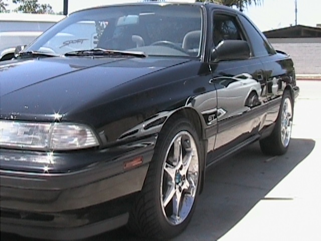 Black Mazda MX-6 GT coupe with chrome five-spoke wheels, 3/4 front view