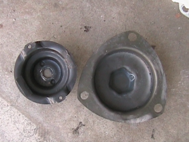 Two used three-bolt upper strut mounts on a concrete garage floor