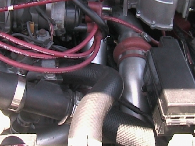 Engine bay close-up with red Magnecor plug wires and red silicone intake elbow