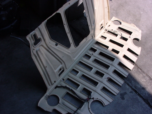 Beige car interior panel with cutouts and wiring, viewed from above