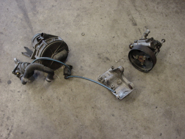 Three automotive parts, including a power steering pump, on a concrete floor