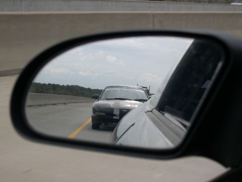 1997 Ford Probe - View of a car from a side mirror on a highway with another vehicle following closely.