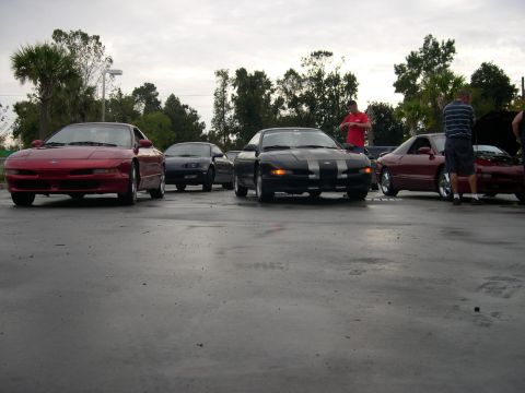 1997 Ford Probe - Several Ford Probes are gathered, with a red one in the foreground and a black one with racing stripes in the middle.