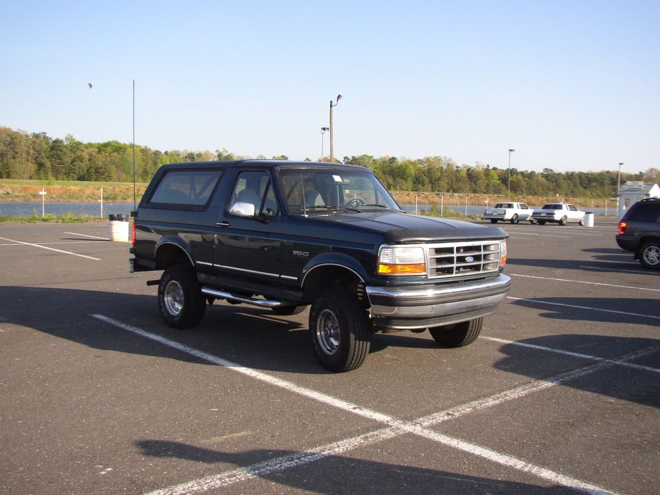 Dark green lifted two-door Ford Bronco 4x4 parked in a lot, front-right three-quarter view