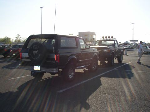 1995 Ford Bronco - A black Ford Bronco is parked at an outdoor event, with another truck nearby.