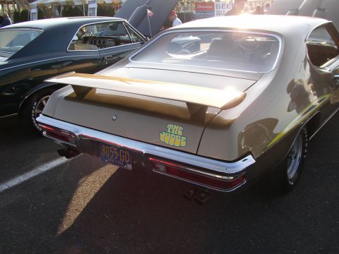 1995 Ford Bronco - A gold Pontiac GTO, known as "The Judge", is parked at an outdoor event with another classic car beside it.