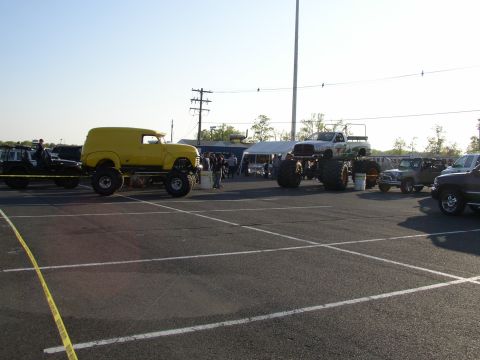 1995 Ford Bronco - Several modified vehicles, including a yellow panel van and a monster truck, are parked at an outdoor event.