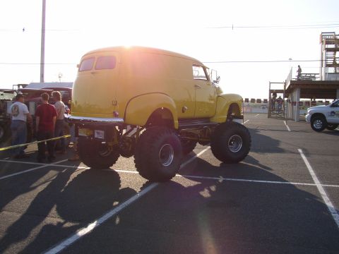 1995 Ford Bronco - A yellow panel van has been converted into a monster truck with oversized tires and lifted suspension.