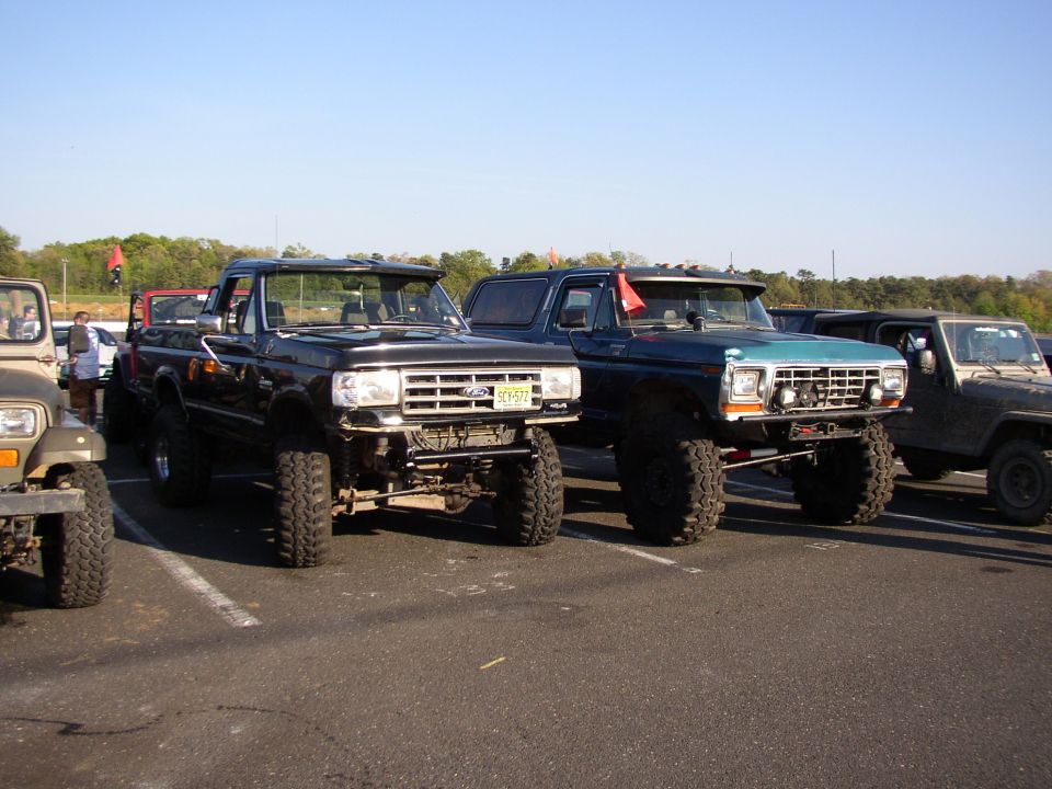 Lifted 1980s Ford F-Series truck and a lifted Ford Bronco parked in a lot