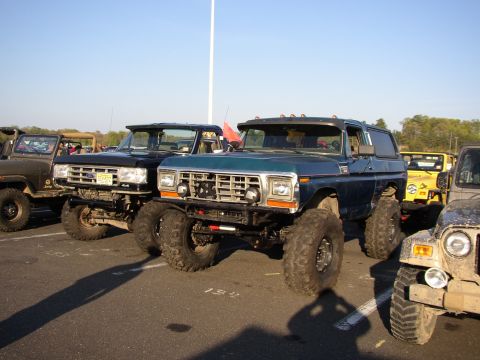 1995 Ford Bronco - A lifted blue Ford Bronco is parked alongside other off-road vehicles at a cruise night event.
