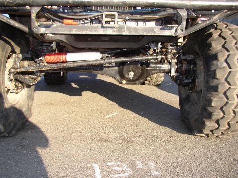 1995 Ford Bronco - Close-up view of the front axle and suspension system of a heavily modified off-road vehicle.