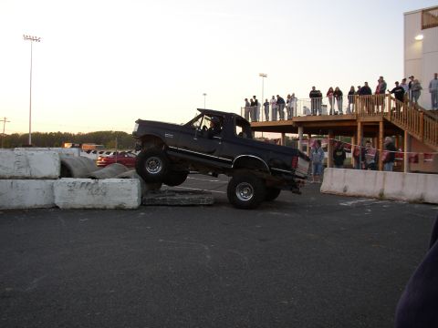 1995 Ford Bronco - A modified pickup truck navigates an obstacle course at an outdoor event.
