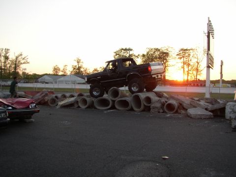 1995 Ford Bronco - A black SUV is positioned on a pile of concrete pipes with a sunset in the background.