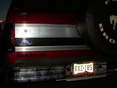 1995 Ford Bronco - Night shot of the rear of a red Ford Bronco showing the tailgate's brushed-aluminum panel and blue Ford oval, an "Official Jeep Recovery Ve…