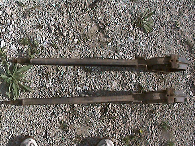 two truck axles lying on gravel