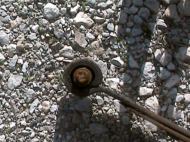 Leaf spring bushing on gravel ground. Supermotors.net logo visible