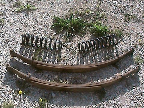 1977 Ford F-150 - Leaf springs and coil springs are shown resting on a gravel surface.